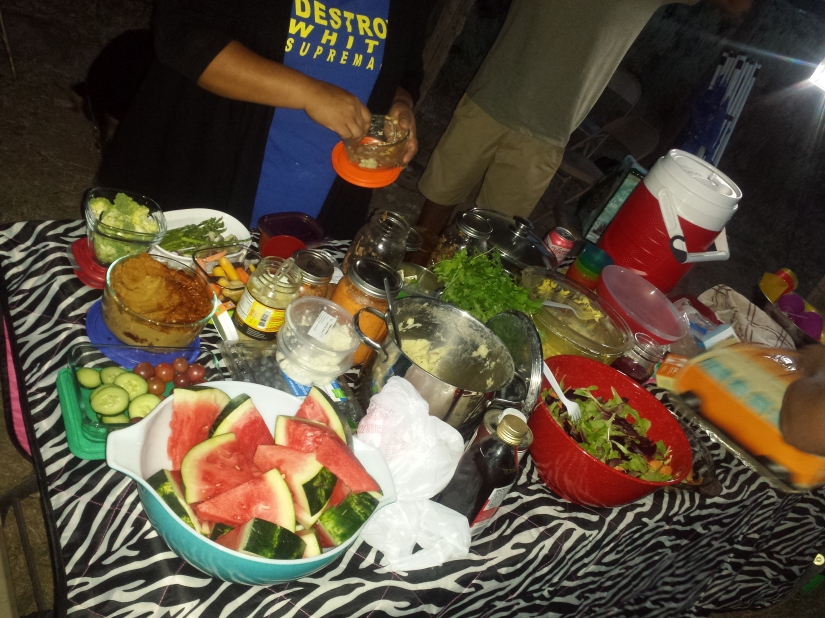 A potluck spread featuring cultural foods and community member with a shirt that reads Destroy white supremacy