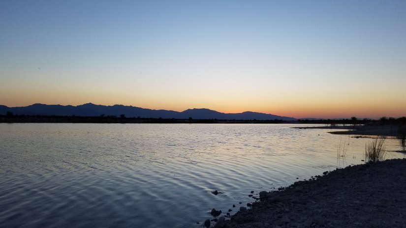 The Sund drops below the horizon as colour fills the clear blue sky reflecting in the Lake.