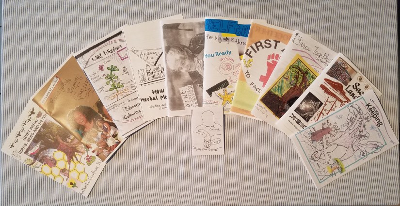 Spread of our 11 zines on a blue striped cloth