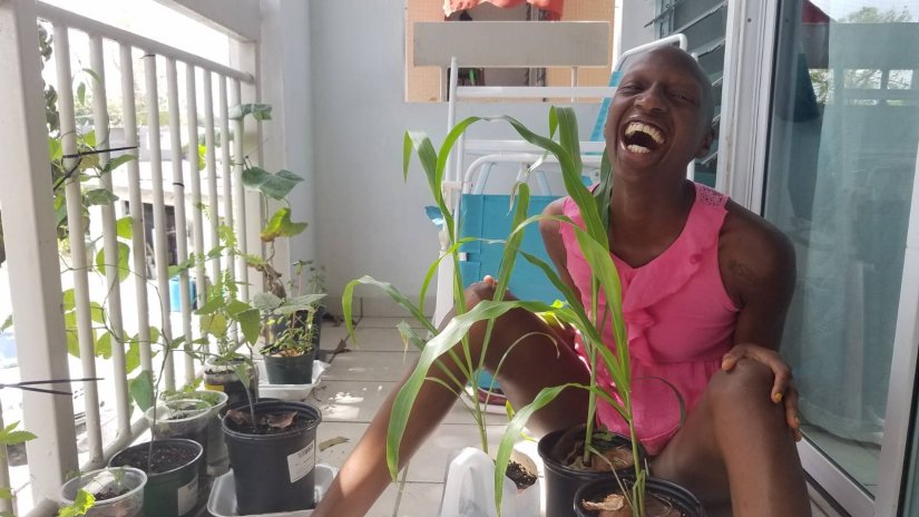 kuwa jasiri (the one) laughs while on the porch interacting with the container garden