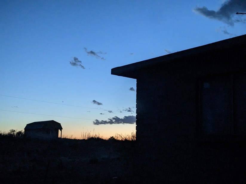 At Dusk the colors are peach and sky blue. The silhouettes of houses and clouds.